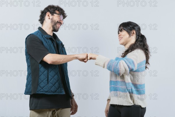 Smiling couple bumping fists, isolated. Attractive couple smiling and bumping fists