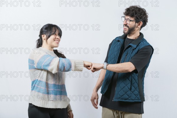 Attractive couple smiling and bumping fists. Smiling couple bumping fists, isolated