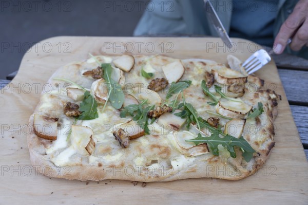Flammkuchen with goat cheese, pears and nuts served on a wooden board, Ahrenshoop, DarÃŸ, Mecklenburg-Western Pomerania, Germany