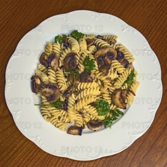 Simple Italian dish pasta fusilli with mushrooms garnished with parsley, vegan cuisine, international