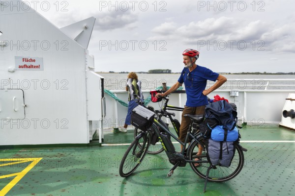 Cyclist with helmet, bicycle tour, e-bike with luggage bags on a ferry, Baltic Sea, Germany