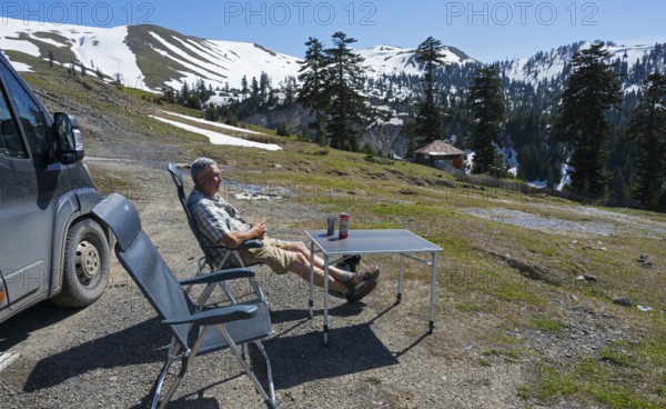 A man relaxing next to a van in a sunny mountain landscape, view from Goderdzi Pass, Ajara region, Adjara, Autonomous Republic, Georgia