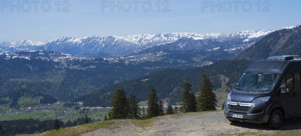 A van parks with a view of a snowy mountain landscape and green forests, camper, view from Goderdzi Pass, Ajara region, Adjara, Autonomous Republic, Georgia