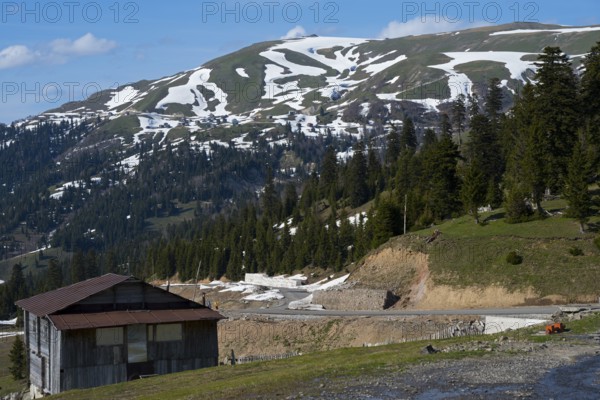 A mountainous landscape with snow-covered hills, forest and a hut in peaceful nature, on the Goderdzi Pass, Ajara region, Adjara, autonomous republic, Georgia