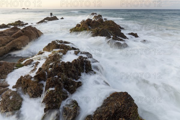 The Cape Byron Lookout at high tide. Rocks and anglers in golden light. Byron Bay, New South Wales, Australia