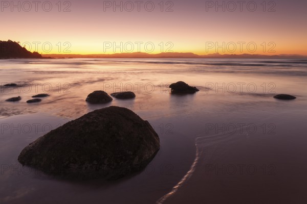 Washed stones and rocks on a beach at sunset in Byron Bay, Wategos Beach, New South Wales, Australia