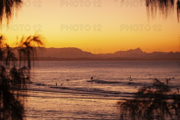 View of the ocean and Wategos Beach on the promenade at sunset. Mt- Warning, Wollumbin in the background of the red sunset on the beach. Byron Bay, New South Wales, Australia