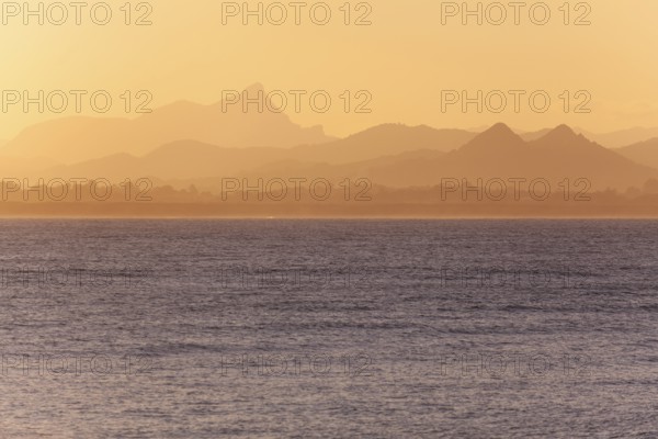 View of the ocean and Byron Bay hinterland at sunset. Mt. Warning, Wollumbin National Park over the bay in the evening light. New South Wales, Australia