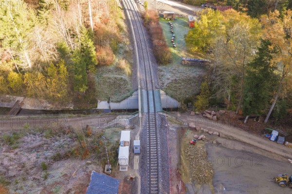 Autumn aerial view of railroad crossing and tracks surrounded by trees, Hermann Hesse Railway bat tunnel construction site, Calw, Black Forest, Germany