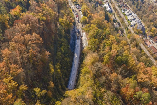 Bird's-eye view of a tunnel construction project integrated into an urban and autumnal forest landscape, Hermann Hesse Railway Bat Tunnel construction site, Calw, Black Forest, Germany