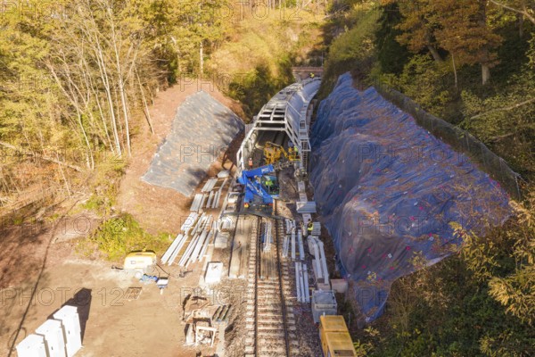 View from above of tunnel construction work with protective tarpaulins and building materials in autumn, Hermann Hesse Railway bat tunnel construction site, Calw, Black Forest, Germany
