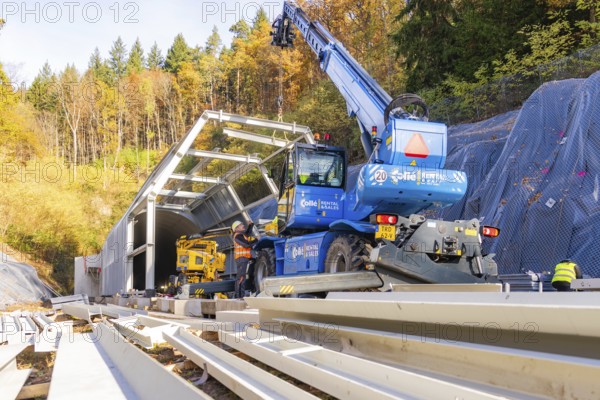 Workers erect a metal structure in front of a tunnel in autumn with crane support, Hermann Hesse Railway bat tunnel construction site, Calw, Black Forest, Germany