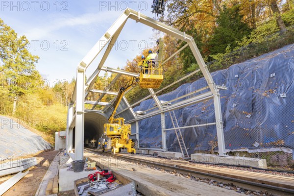 Construction work on a tunnel opening with cranes and workers against an autumn backdrop, Hermann Hesse Railway bat tunnel construction site, Calw, Black Forest, Germany