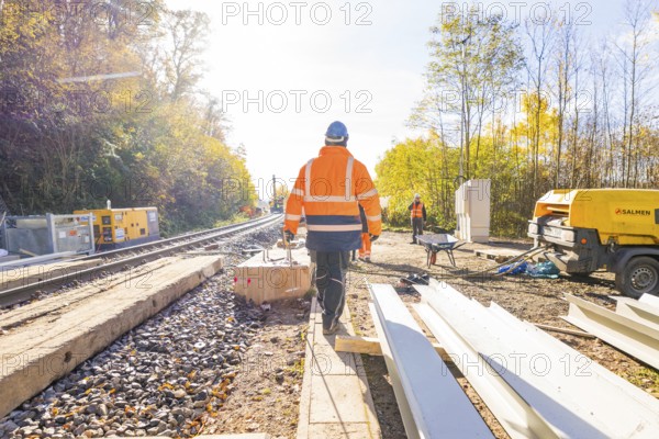 Construction workers in glowing vests work on a railway construction site under clear skies, Hermann Hesse Railway Bat Tunnel construction site, Calw, Black Forest, Germany