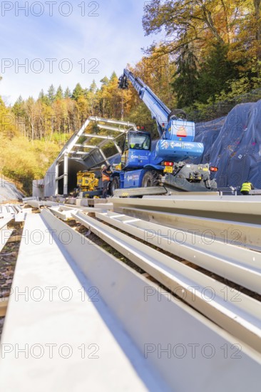 View of large cranes working on a rail structure surrounded by trees, Hermann Hesse Railway Bat Tunnel construction site, Calw, Black Forest, Germany