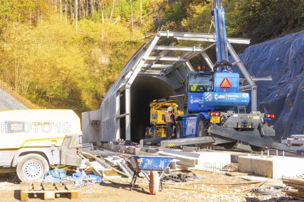 Construction site in front of a tunnel with machinery surrounded by autumn trees, Hermann Hesse Railway bat tunnel construction site, Calw, Black Forest, Germany