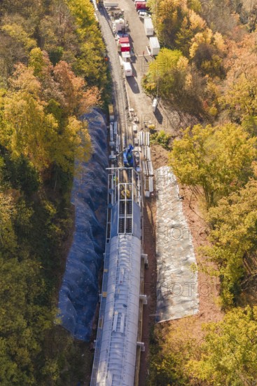Material transport on a tunnel construction site, nestled in autumn forest from a bird's eye view, Hermann Hesse Railway Bat Tunnel construction site, Calw, Black Forest, Germany
