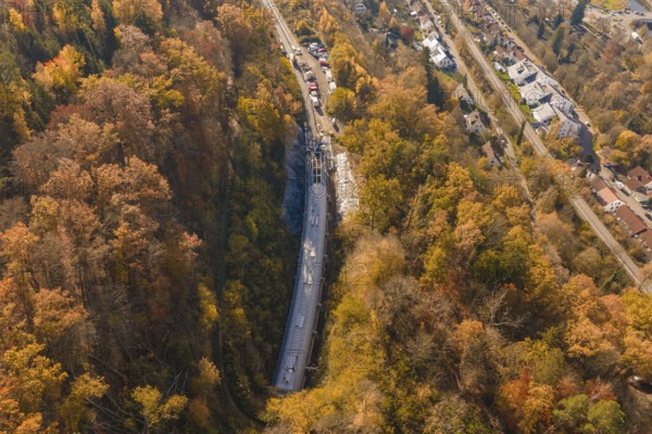 Aerial view of a construction site in colorful autumn forest with adjacent roads and houses, Hermann Hesse Railway bat tunnel construction site, Calw, Black Forest, Germany