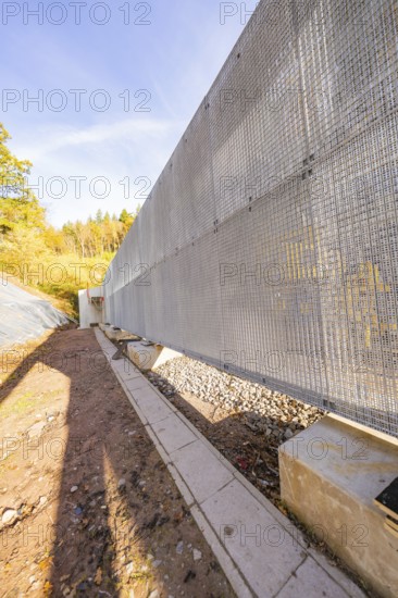 A long metal protective wall along a building area in an autumn landscape, Hermann Hesse Railway bat tunnel construction site, Calw, Black Forest, Germany