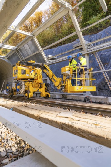 Two workers operate yellow machines in a partially built metal structure, Hermann Hesse Railway Bat Tunnel construction site, Calw, Black Forest, Germany