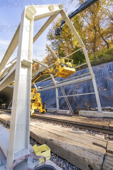 Construction workers erect a metal structure on rails along a wooded area, Hermann Hesse Railway bat tunnel construction site, Calw, Black Forest, Germany