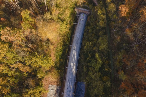 Autumn forest frames a tunnel construction project, shown in a colorful aerial view, Hermann Hesse Railway Bat Tunnel construction site, Calw, Black Forest, Germany