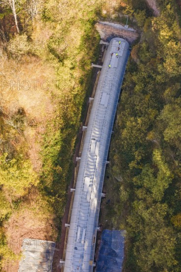 Tunnel construction viewed from above, nestled in a dense autumn forest with colorful leaves, Hermann Hesse Railway bat tunnel construction site, Calw, Black Forest, Germany