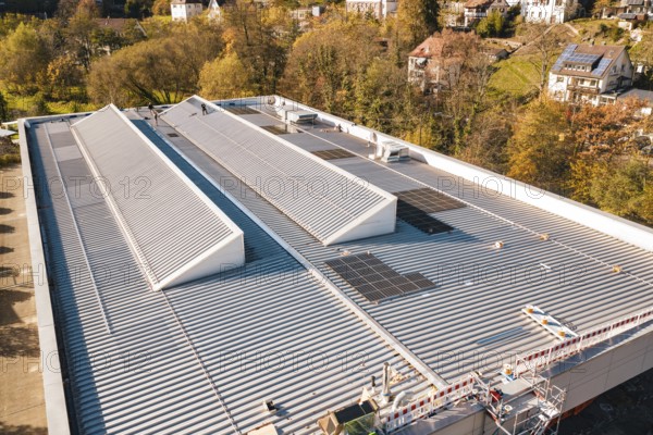 Detailed view of a modern building roof with solar cells, surrounded by trees, PV at Walther Lindner Sporthalle Calw, Black Forest, Germany