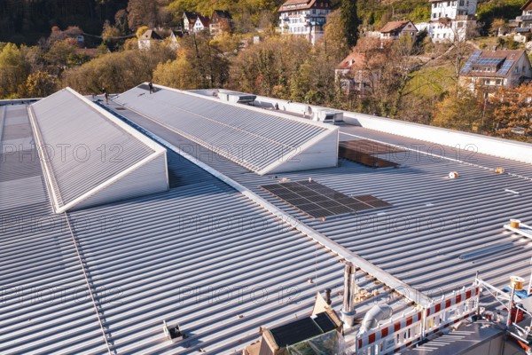 Close-up of a roof with solar panels in the middle of an autumn village landscape, PV at Walther Lindner Sporthalle Calw, Black Forest, Germany