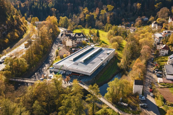 Building with solar panels in the middle of a picturesque autumn landscape with river and forest, PV at Walther Lindner Sporthalle Calw, Black Forest, Germany