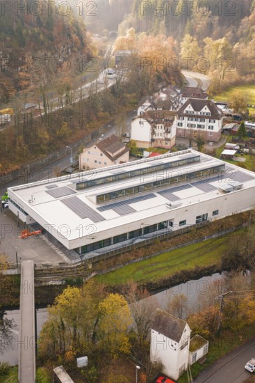 Building with solar panels in an autumn landscape, surrounded by village houses, PV at Walther Lindner Sporthalle Calw, Black Forest, Germany