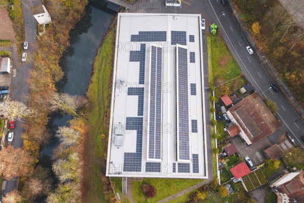 Aerial view of a building with solar panels, surrounded by river and roads, PV at Walther Lindner Sporthalle Calw, Black Forest, Germany