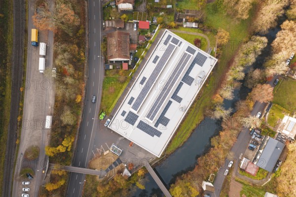 Aerial view of a building with solar panels, surrounded by river and trees, PV at Walther Lindner Sporthalle Calw, Black Forest, Germany