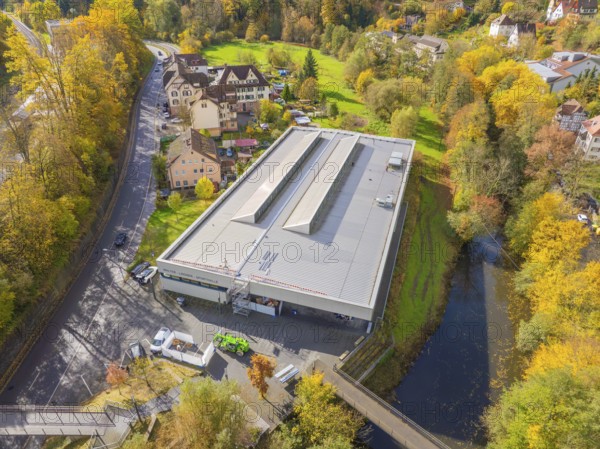 Panorama of a modern building with solar panels, embedded in an autumnal village and river environment, PV at Walther Lindner Sporthalle Calw, Black Forest, Germany