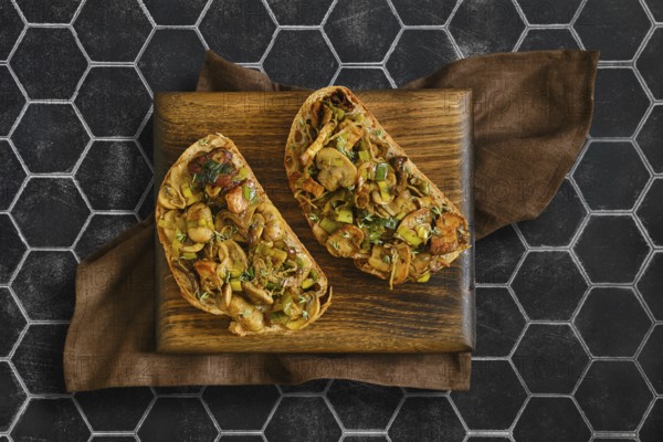 Two sandwiches with flavorful mix of honey mushrooms, enoki mushrooms, champignon, and leeks. Perfectly presented on a wooden board with a stylish background, inviting a tasty experience