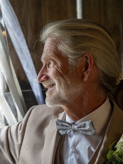 Elderly couple's wedding, groom looking outside, elderly man with long hair, ponytail and bow tie