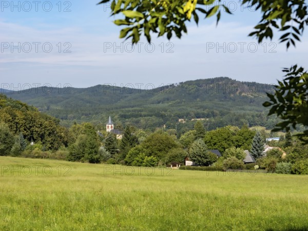 Small village with church in a gentle mountain landscape and meadows, Lusetian Mountains, Bohemia, Czech Republic