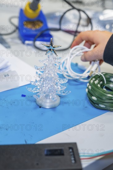 Small plastic Christmas tree on craft table with cable in hand, Jugend Forschungszentrum Nagold, Calw district, Germany
