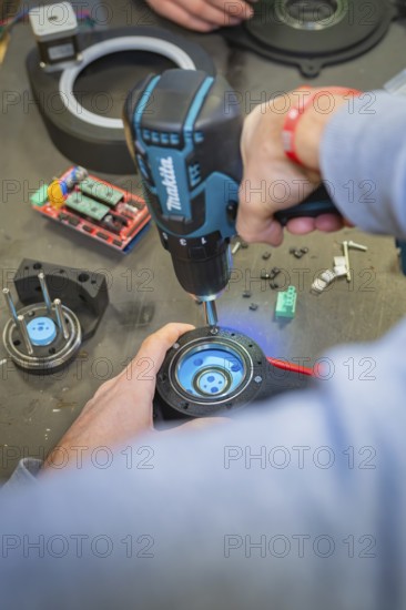 Person using a drill to assemble parts at a table, Jugend Forschungszentrum Nagold, Calw district, Germany