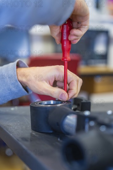 Person uses screwdriver to mount on a technical device, Jugend Forschungszentrum Nagold, Calw district, Germany