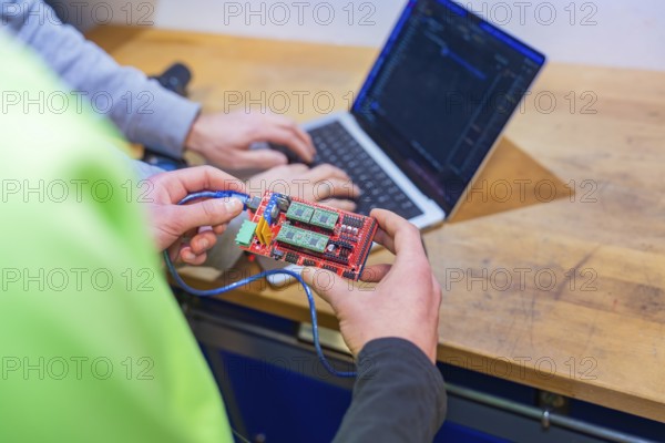 Circuit board is held while someone is working on a laptop, Jugend Forschungszentrum Nagold, Calw district, Germany