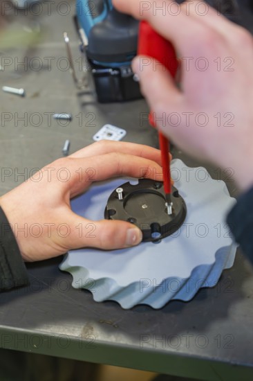 Screwdriver fixes screws to a gear wheel in a workshop environment, Jugend Forschungszentrum Nagold, Calw district, Germany