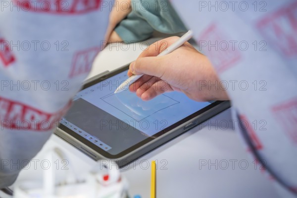Person drawing with a stylus on a tablet surrounded by cool colors, Jugend Forschungszentrum Nagold, Calw district, Germany