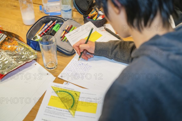 Student draws and solves tasks in a notebook on a table, Jugend Forschungszentrum Nagold, Calw district, Germany
