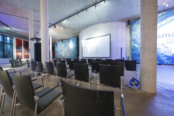 Empty conference room with chairs and a large projection screen under a high roof, Amazonia exhibition, Gasometer, Pforzheim, Germany