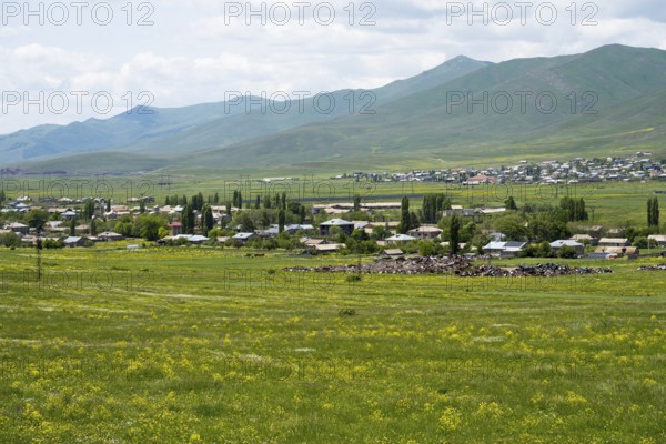 Village in green landscape with meadows and mountains in the background, view of Geghamavan, Gegharkunik province, Armenia
