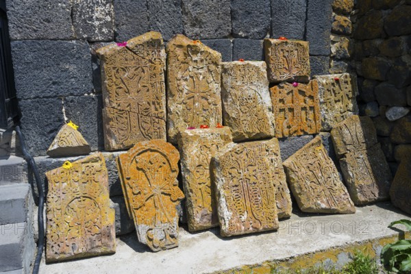 Historical, engraved stones with flowers on concrete in front of a wall, cross stones at Sevanavank monastery, Sevan monastery, Gegharkunik province, Armenia