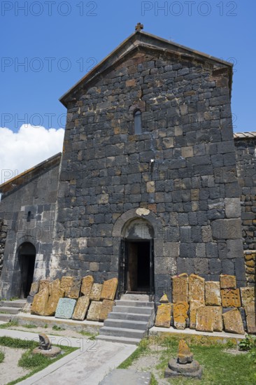 Old stone building with open door and roof under blue sky, cross stones at Sevanavank monastery, Sevan monastery, Gegharkunik province, Armenia