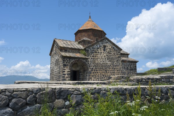 Historic stone church with orange roof against blue sky and white clouds, Sevanavank Monastery, Gegharkunik Province, Armenia