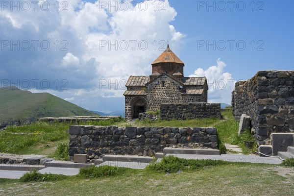 A small stone monastery stands amidst a green landscape under a blue sky, Sevanavank Monastery, Sevan Monastery, Gegharkunik Province, Armenia